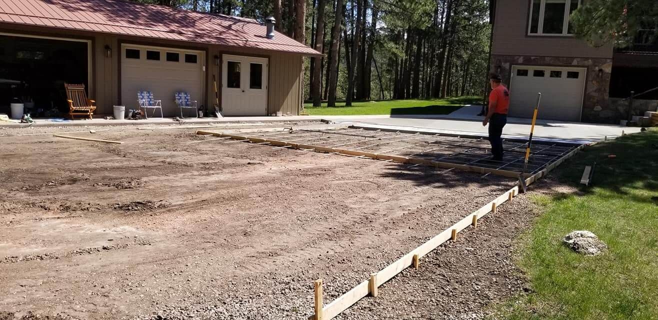 A man is working on a driveway in front of a house.