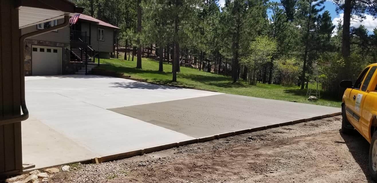 A yellow truck is parked in a driveway next to a house.