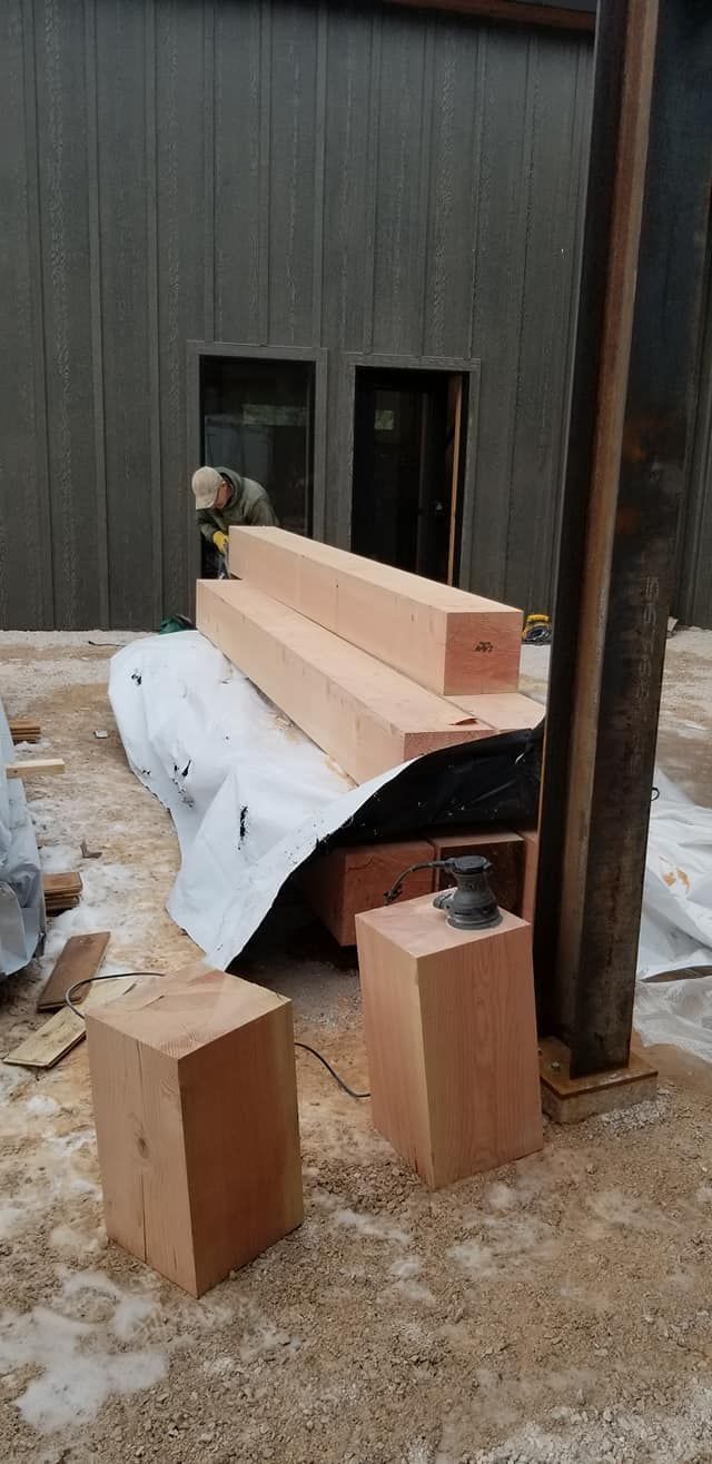 A pile of wood is sitting on the ground in front of a building.