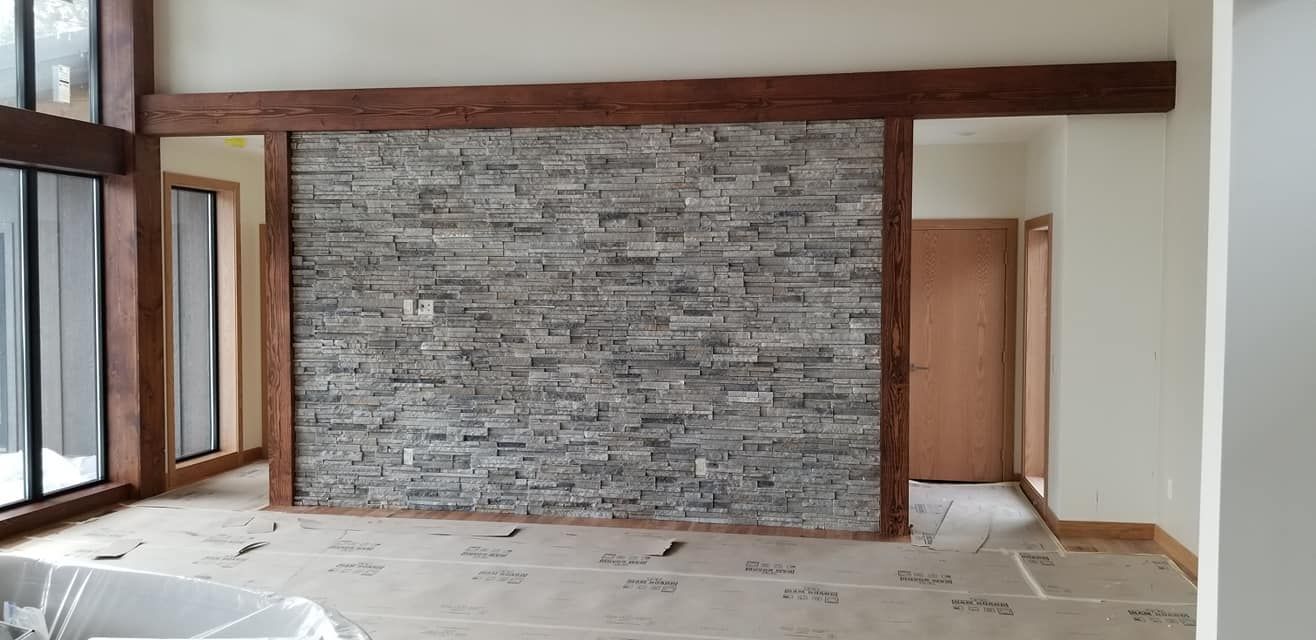 A living room with a stone wall and wooden beams.
