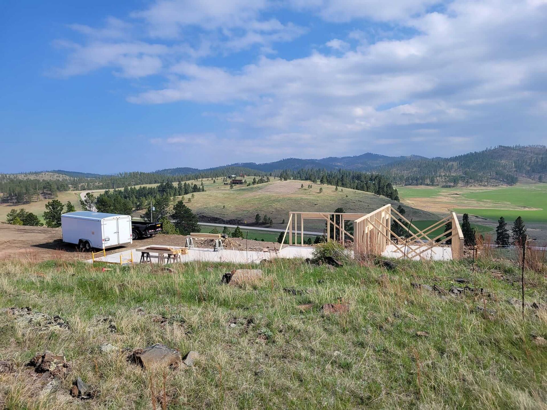 A house is being built on a hill with mountains in the background
