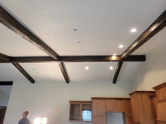 A kitchen with a white ceiling and wooden beams