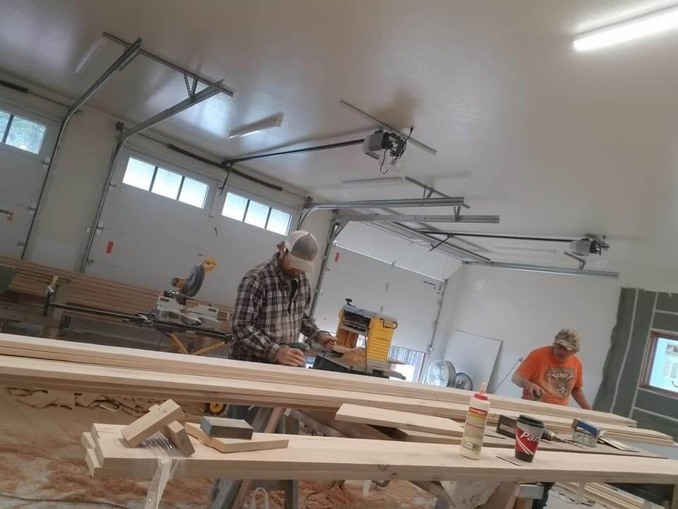 Two men are working on wood in a garage.