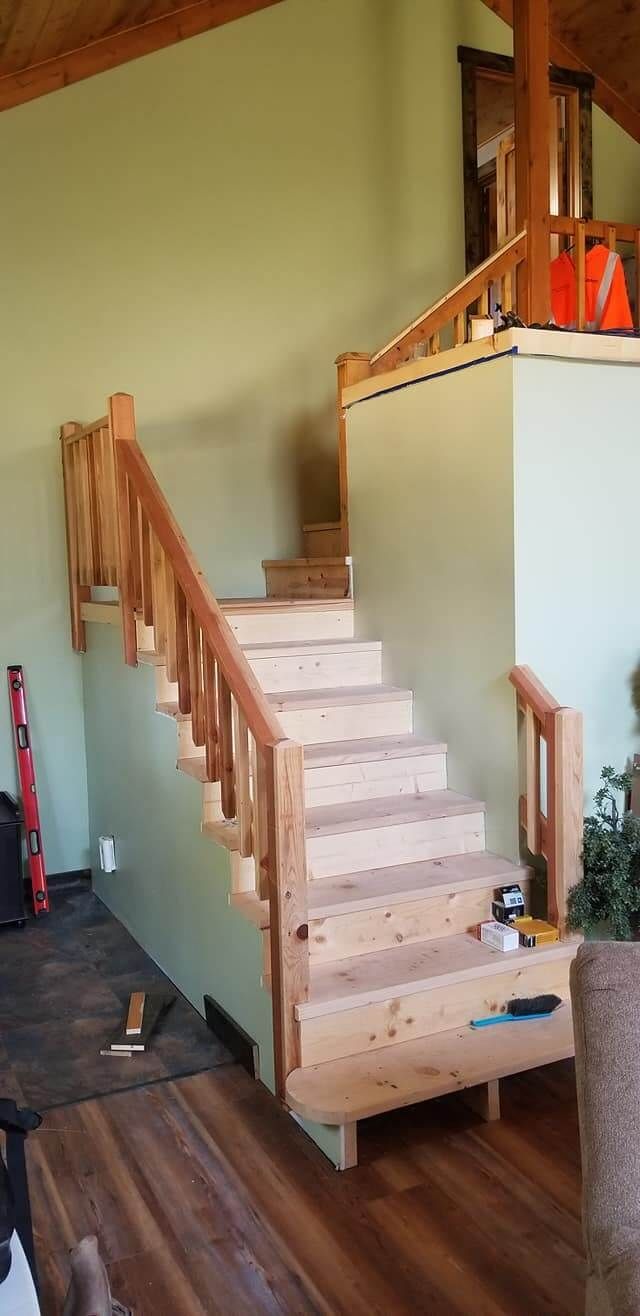 A wooden staircase is being built in a living room.