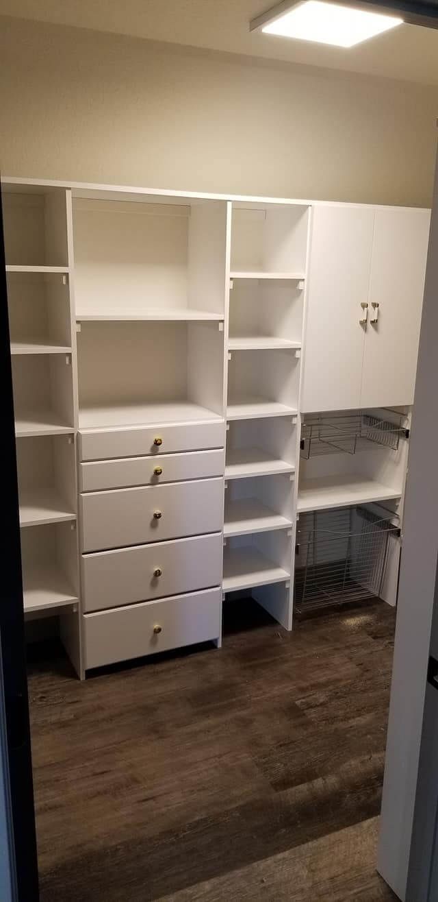 A walk in closet with lots of shelves and drawers.