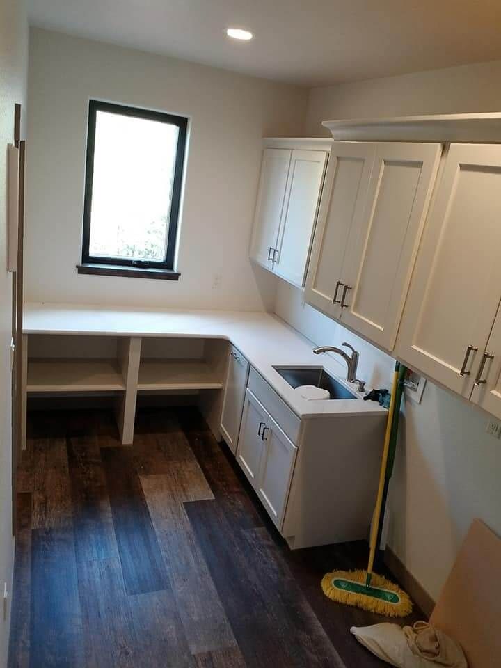 A kitchen with white cabinets a sink and a mop