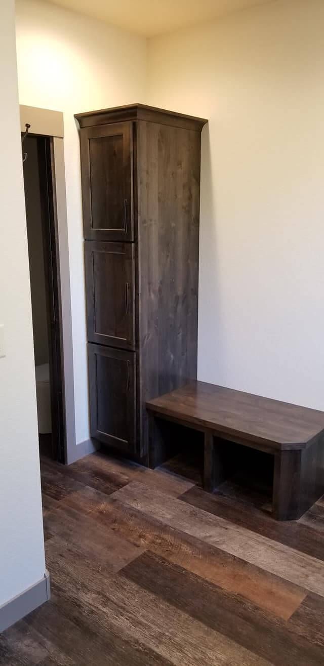 A room with a wooden bench and a wooden cabinet.
