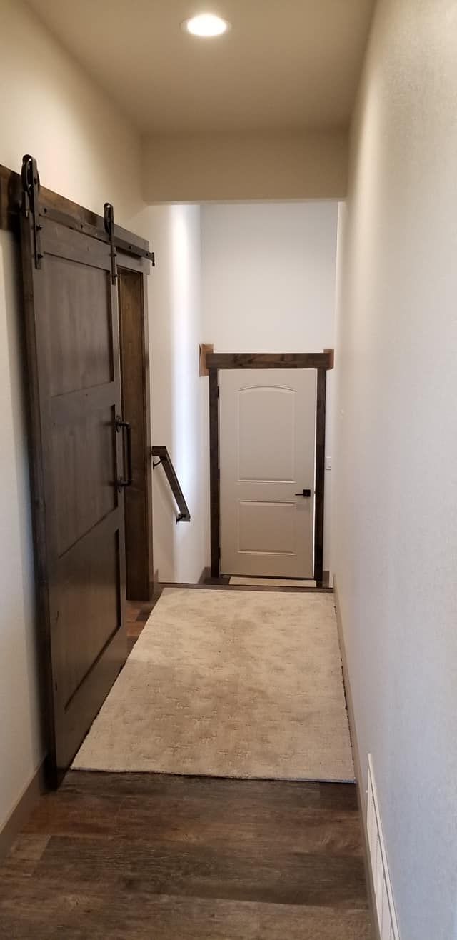 A hallway with a sliding barn door and a white door.