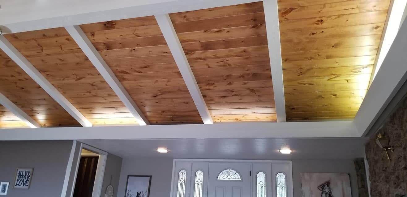 A living room with a wooden ceiling and white beams.