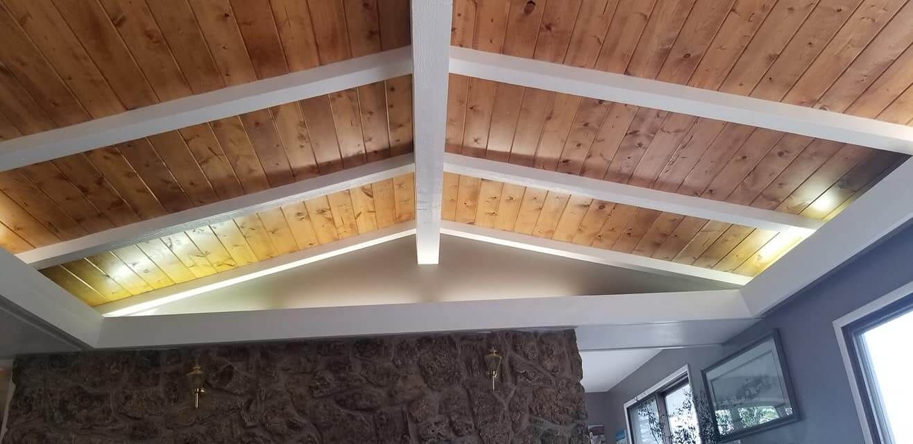 A living room with a wooden ceiling and a fireplace.