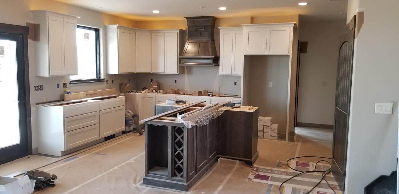 A kitchen under construction with white cabinets and a large island.