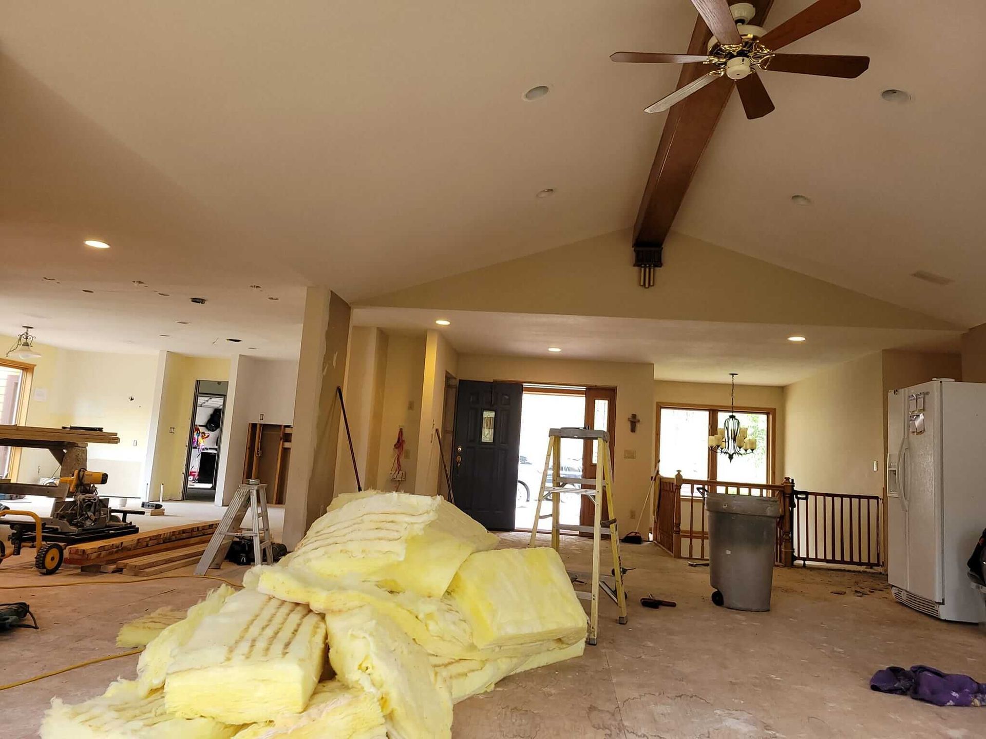 A large room with a ceiling fan and a pile of insulation