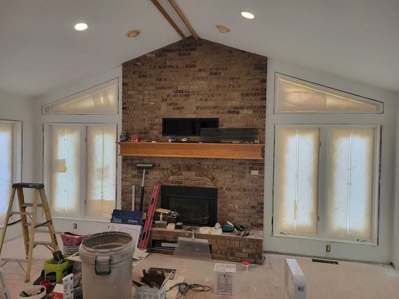A living room with a fireplace and a ladder in it.