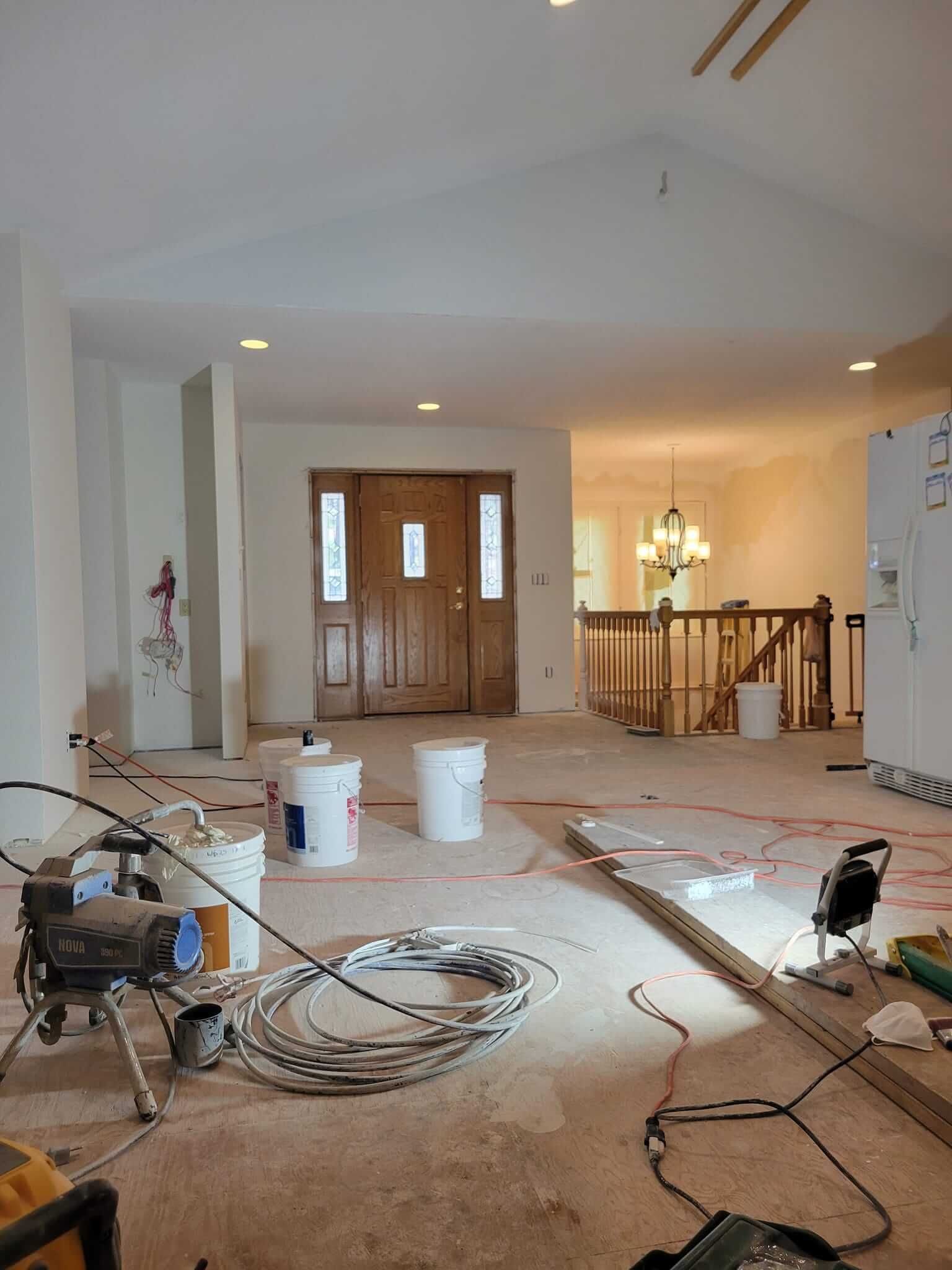 A living room under construction with buckets of paint on the floor.