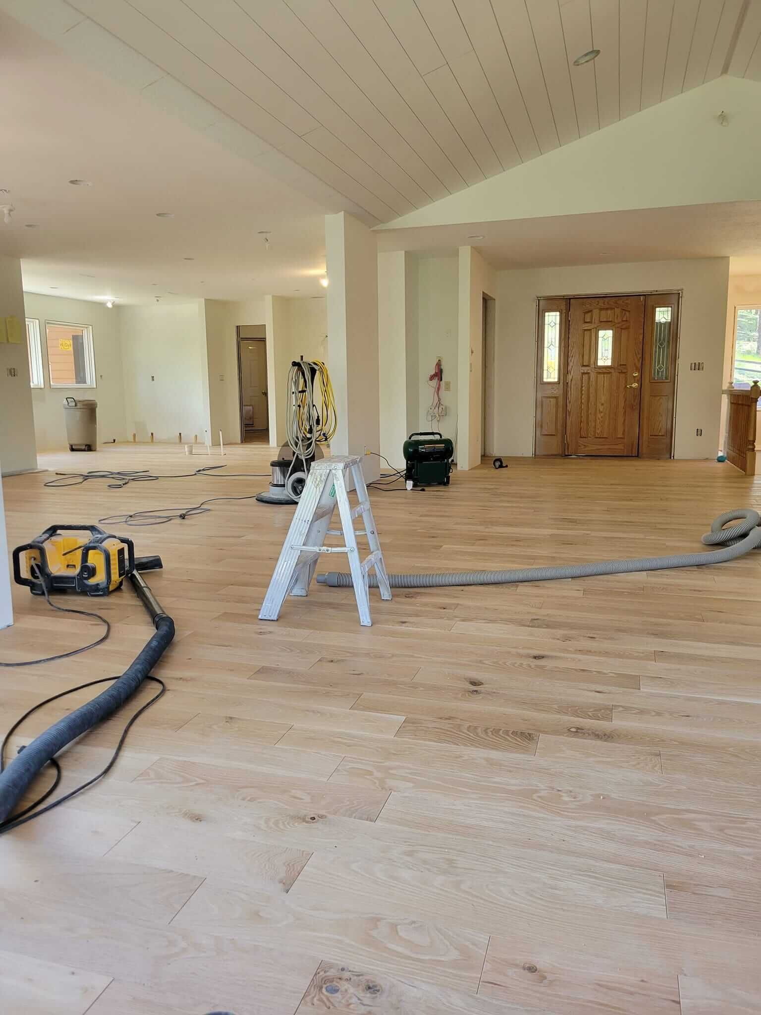 A vacuum cleaner is sitting on a wooden floor in an empty room.