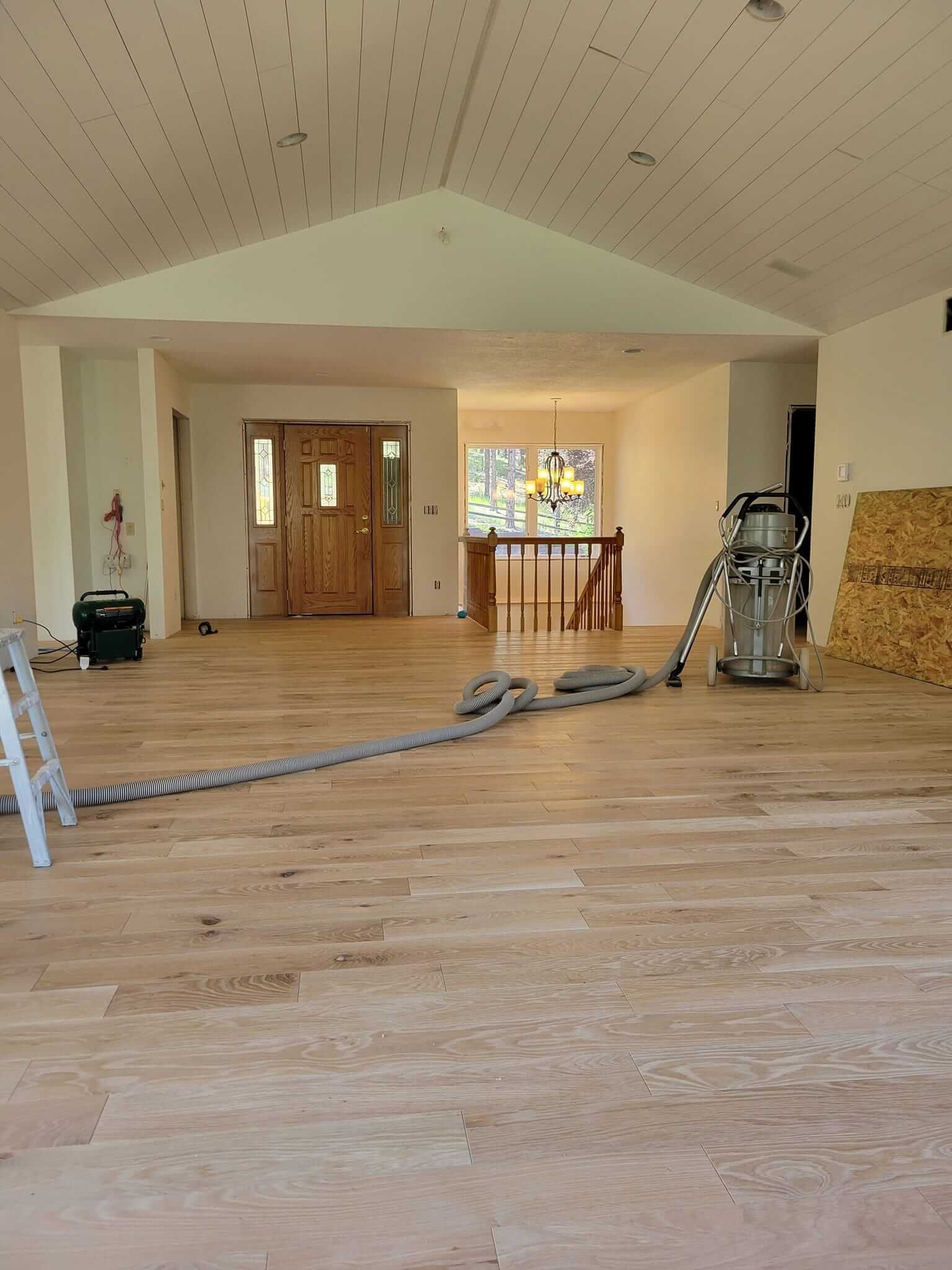 A large empty room with wooden floors and a vacuum cleaner.
