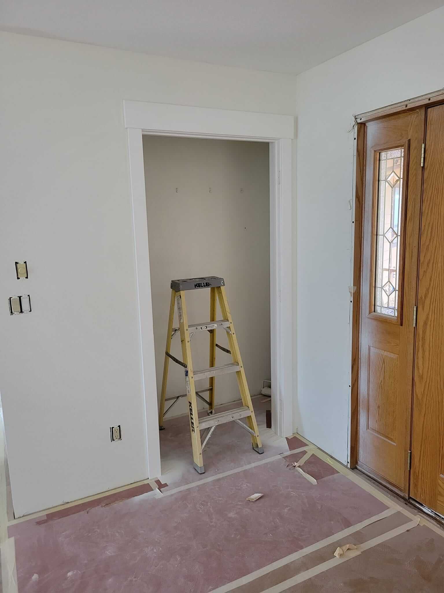 A wooden ladder is sitting in a room next to a door.