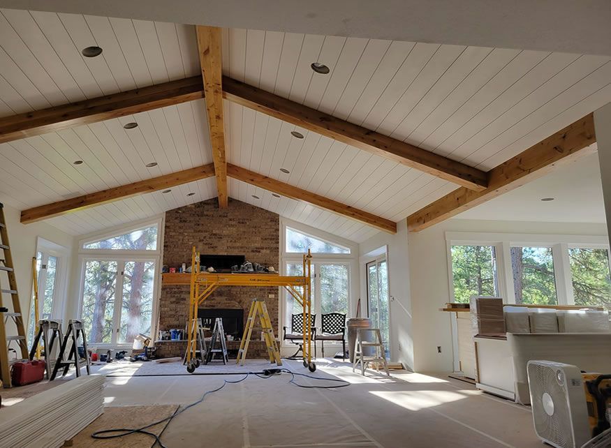 A living room with a vaulted ceiling and a fireplace under construction.