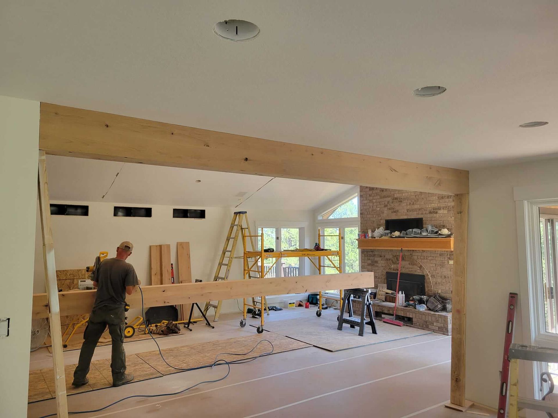 A man is working on a wooden beam in a living room.