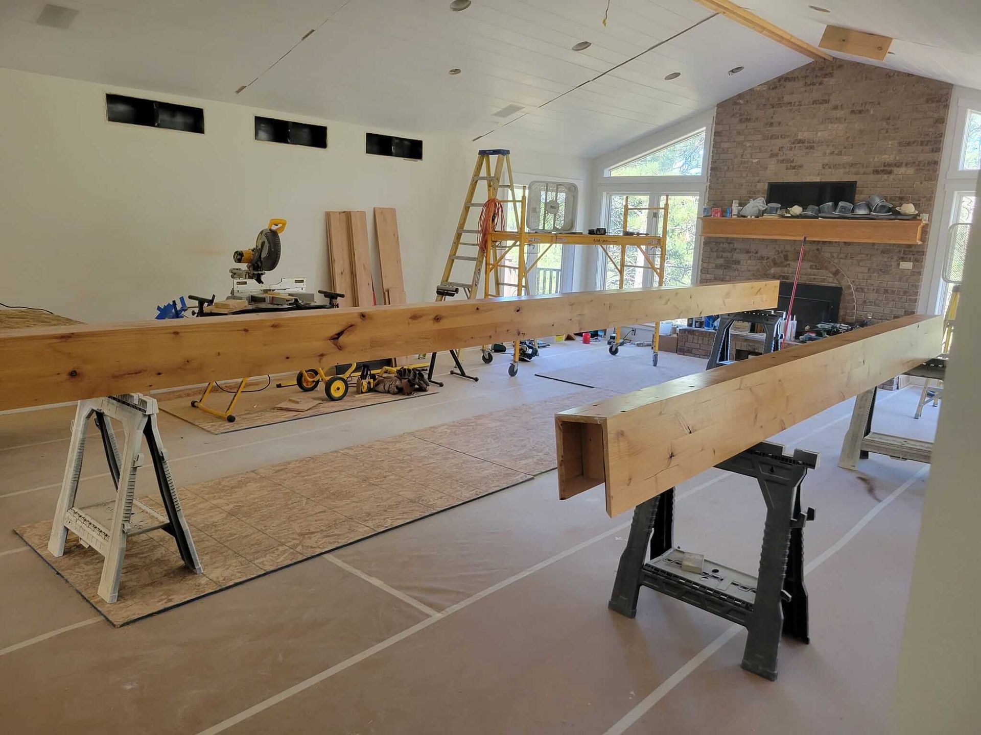 A large wooden beam is sitting on a workbench in a living room.