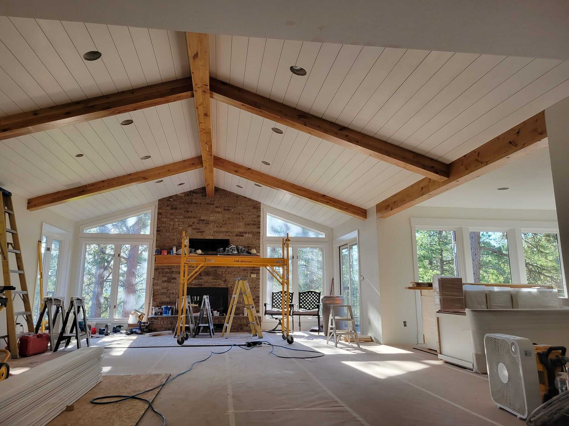 A large living room with a vaulted ceiling and a fireplace under construction.