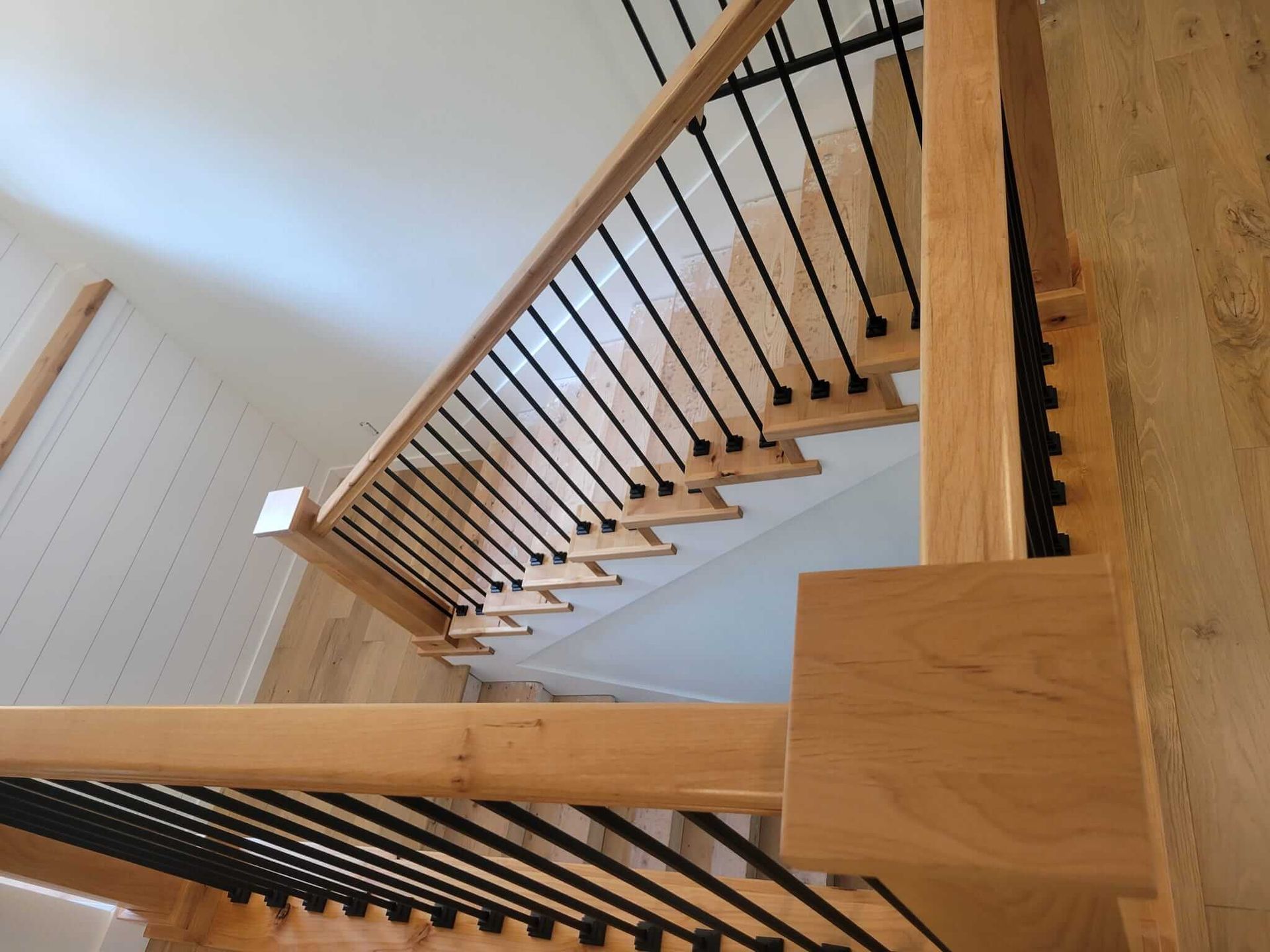 A wooden staircase with a black railing in a house.