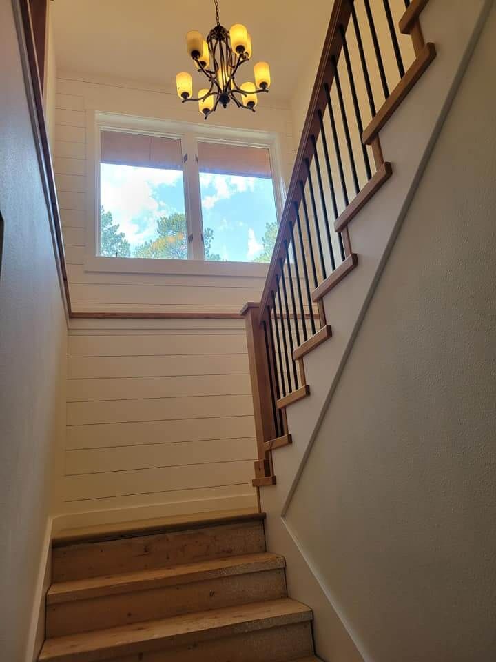 A staircase with a chandelier hanging from the ceiling and a window.