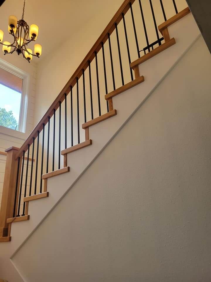 A staircase with a wooden railing and a chandelier hanging from the ceiling