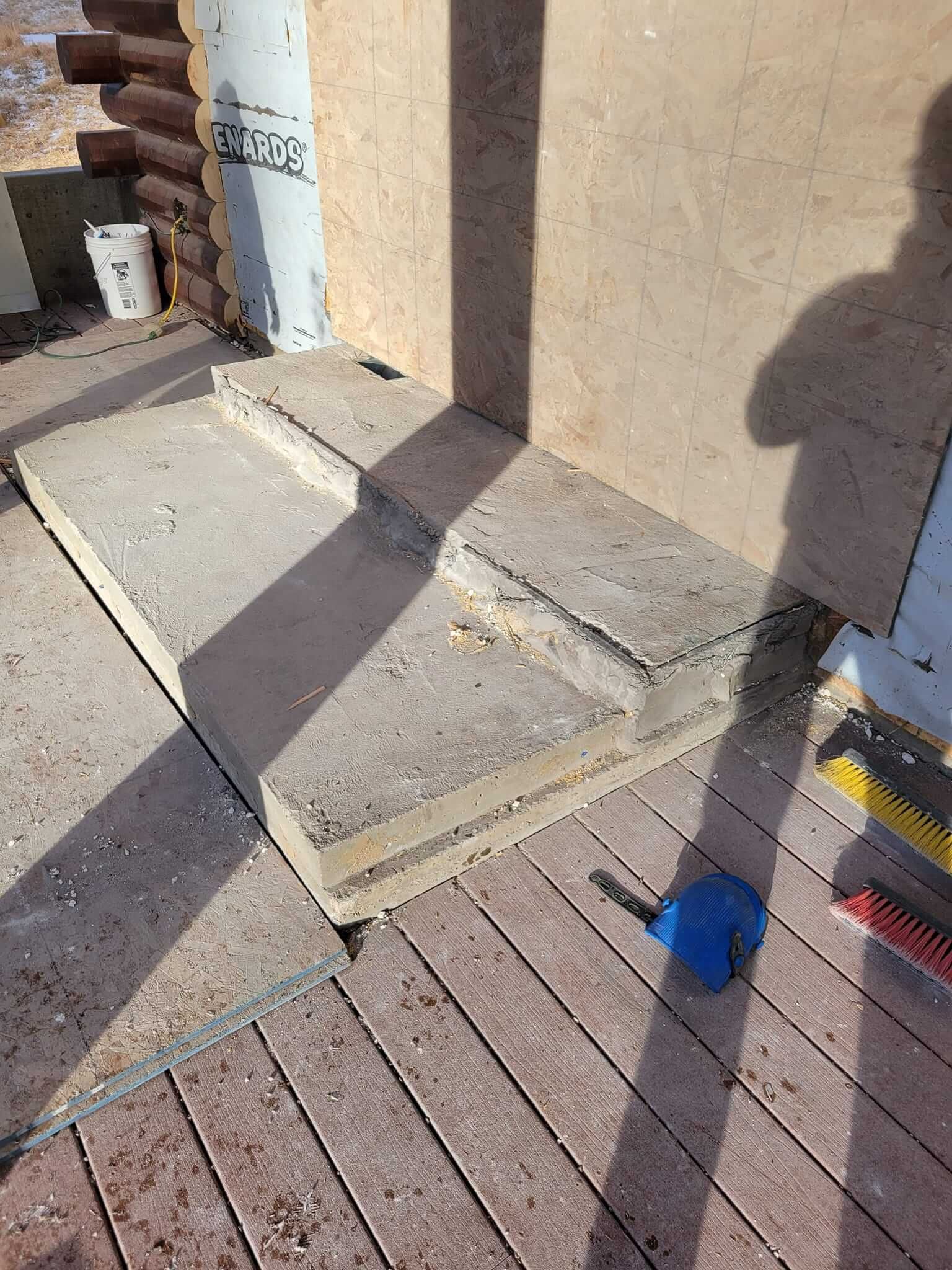 A shadow of a person is cast on a wooden deck.