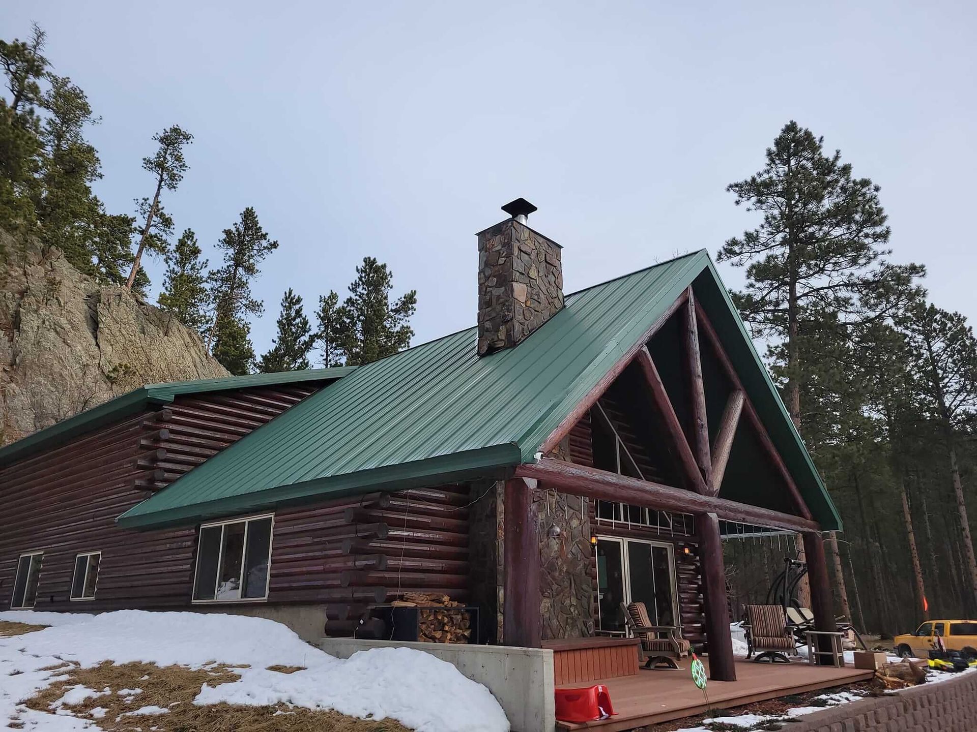 A log cabin with a green roof and a chimney