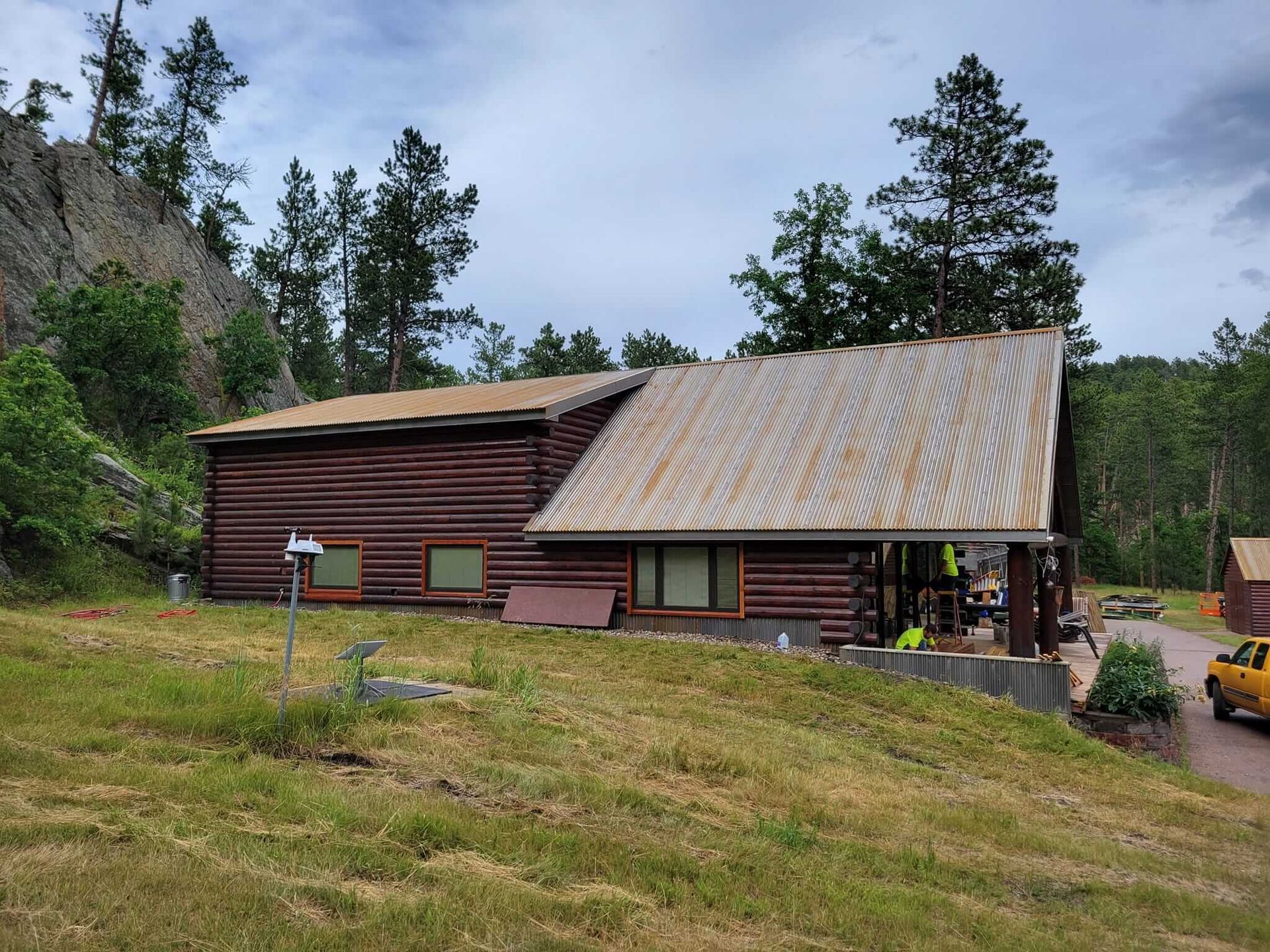 A log cabin with a metal roof is sitting in the middle of a grassy field.