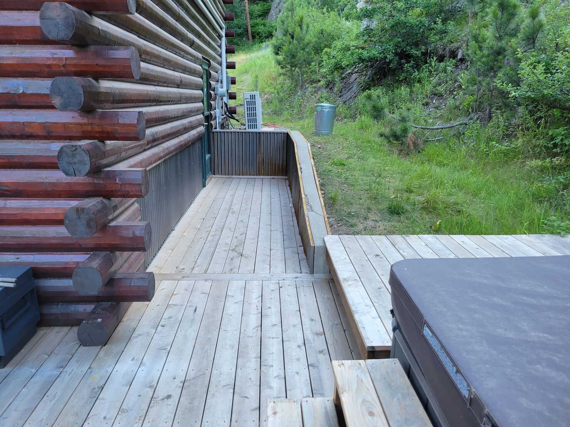 A wooden deck with a hot tub in front of a log cabin