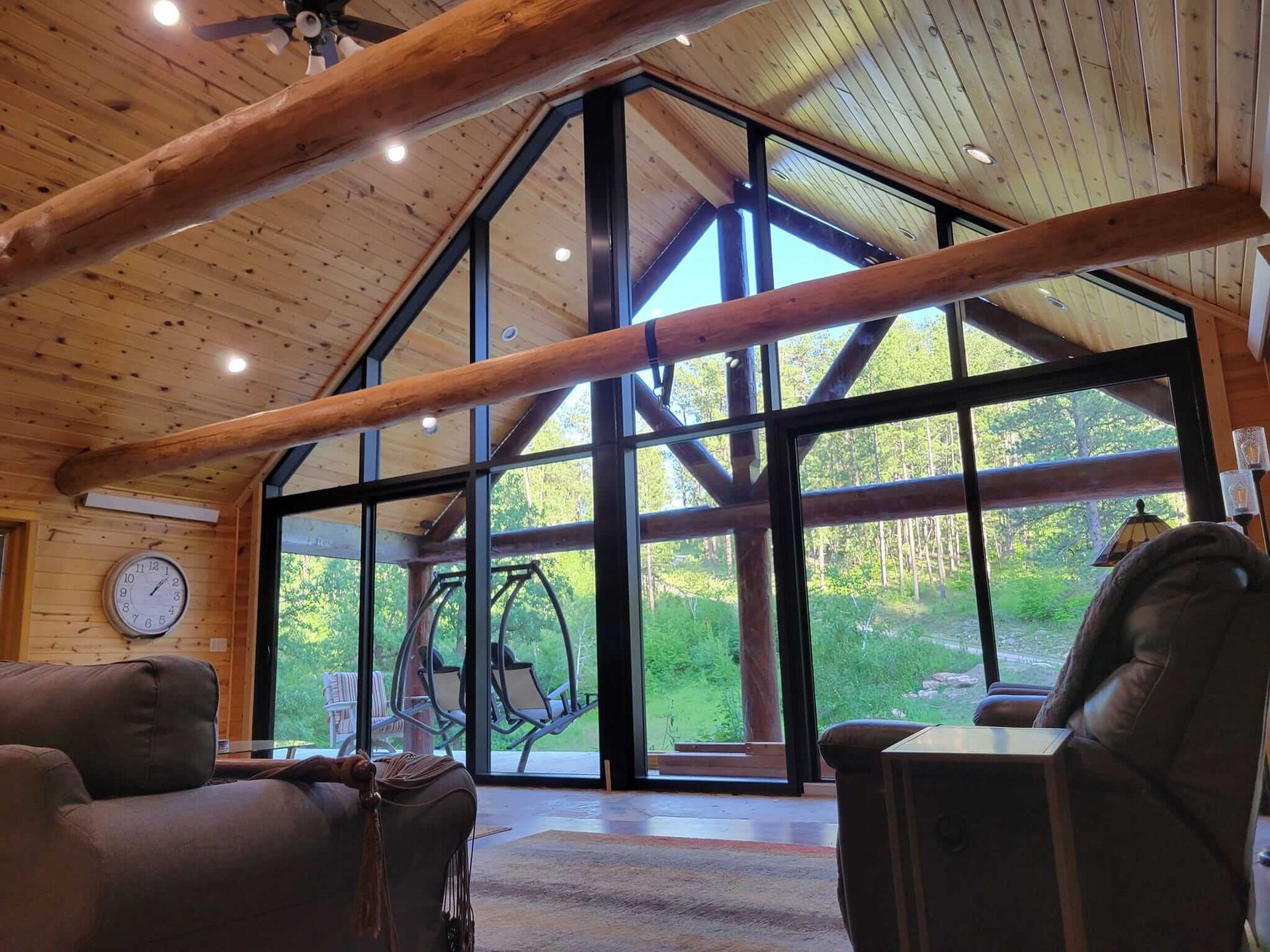 A living room with a lot of windows and a clock on the wall.