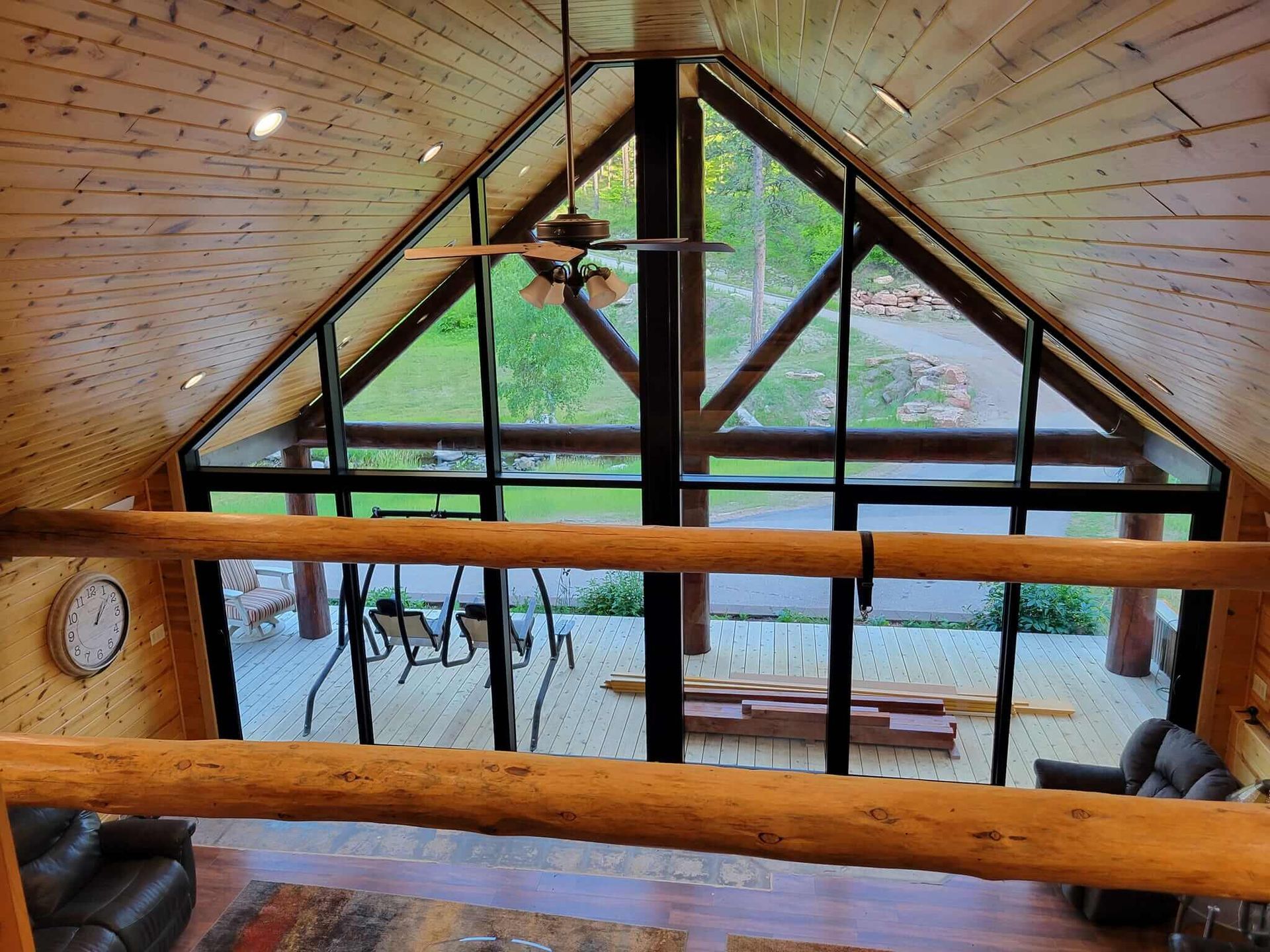 A living room with a lot of windows and a ceiling fan