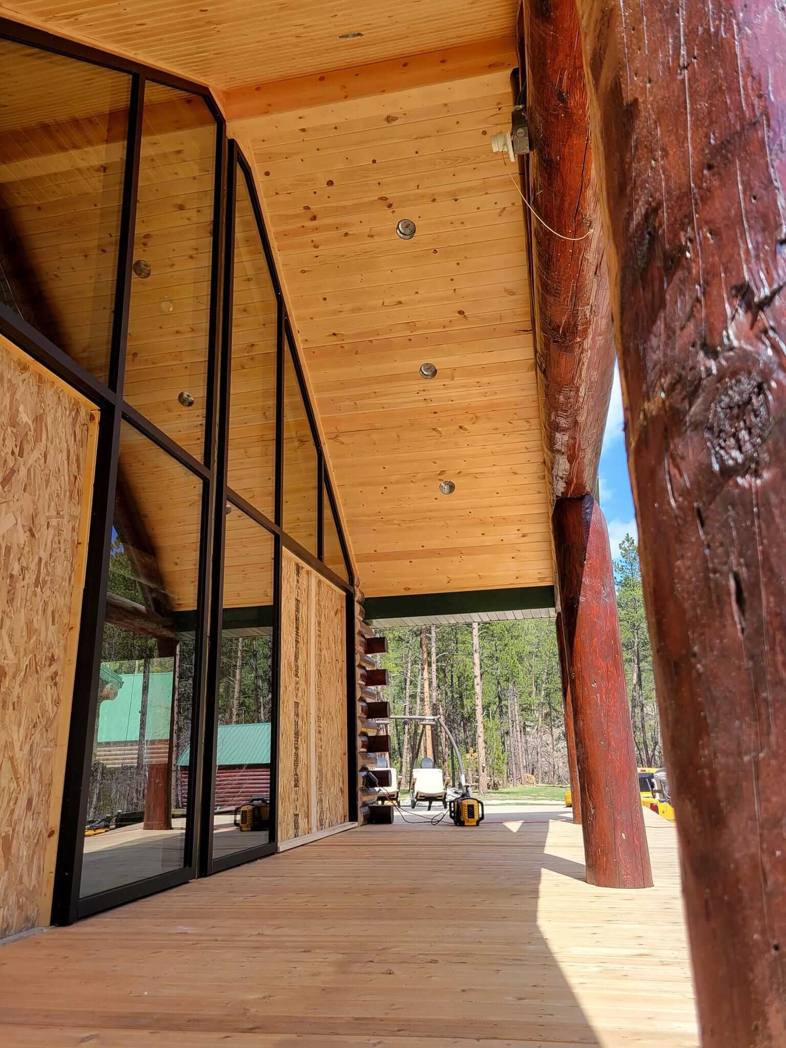A wooden porch with a lot of windows and a tree in the background.