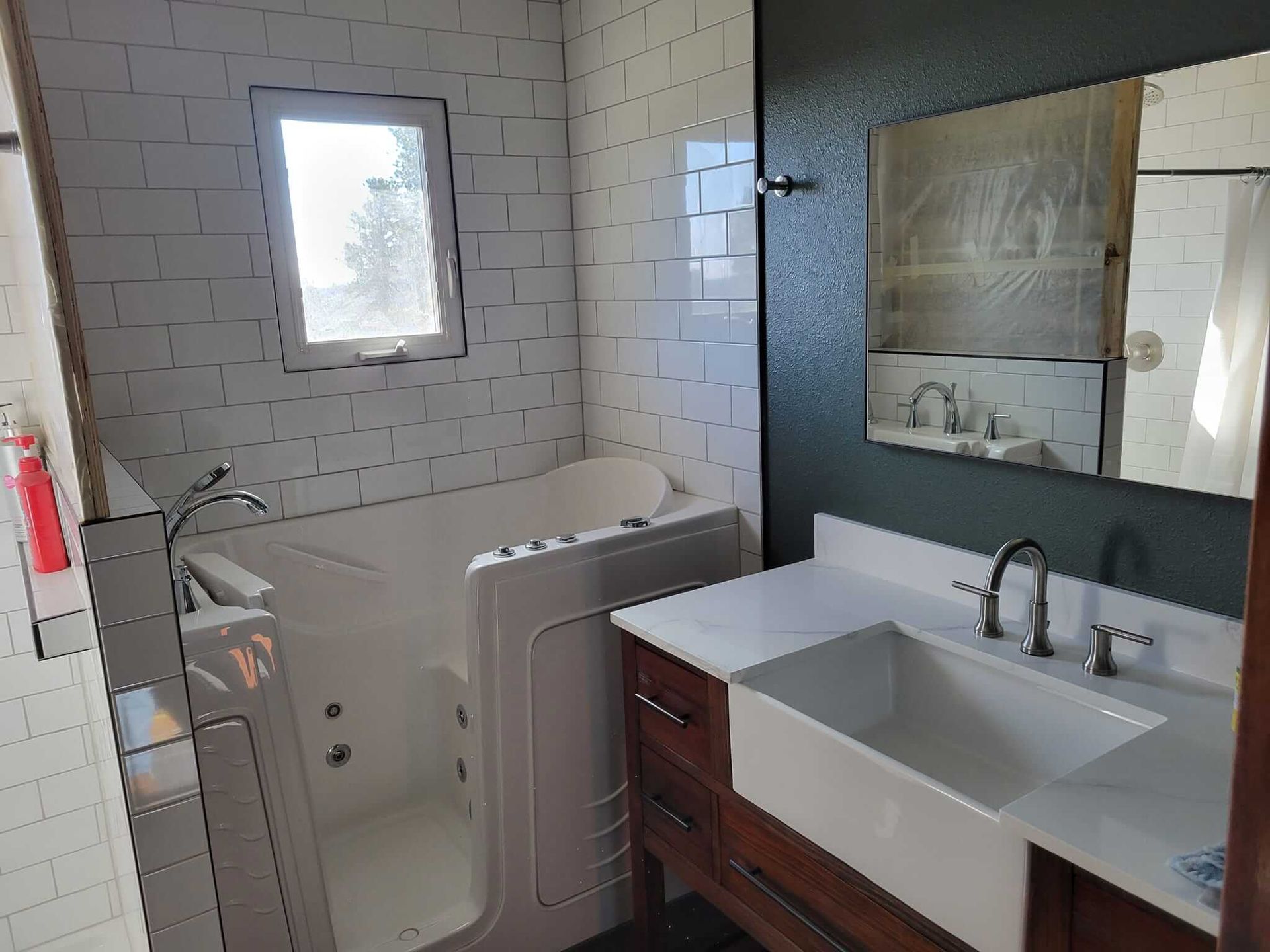 A bathroom with a walk-in tub, sink, and mirror.