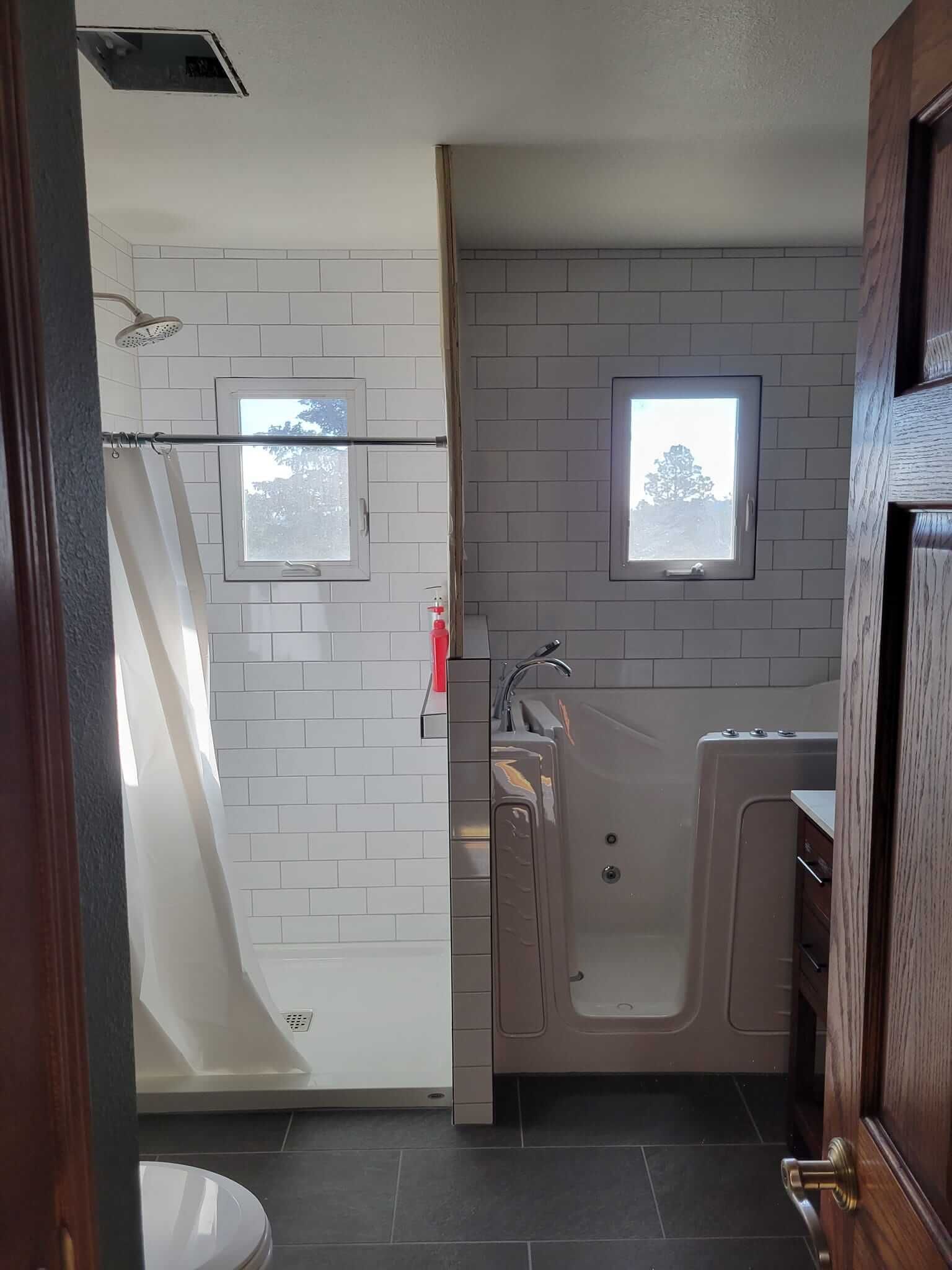 A bathroom with a walk-in tub, shower, sink, and toilet.