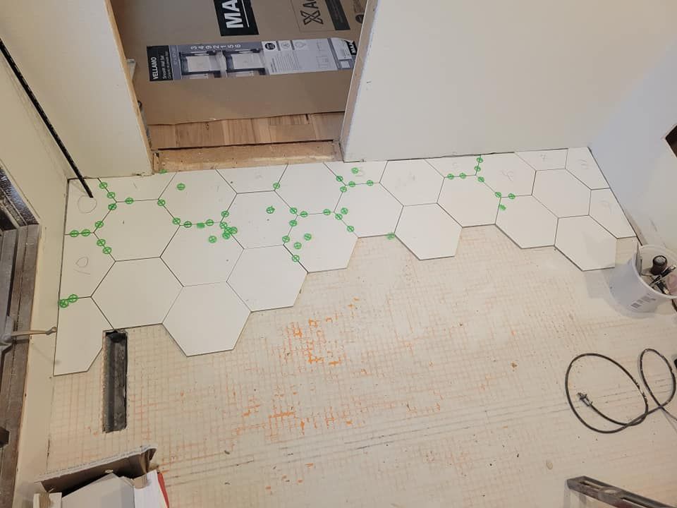 A white tile floor is being installed in a room.