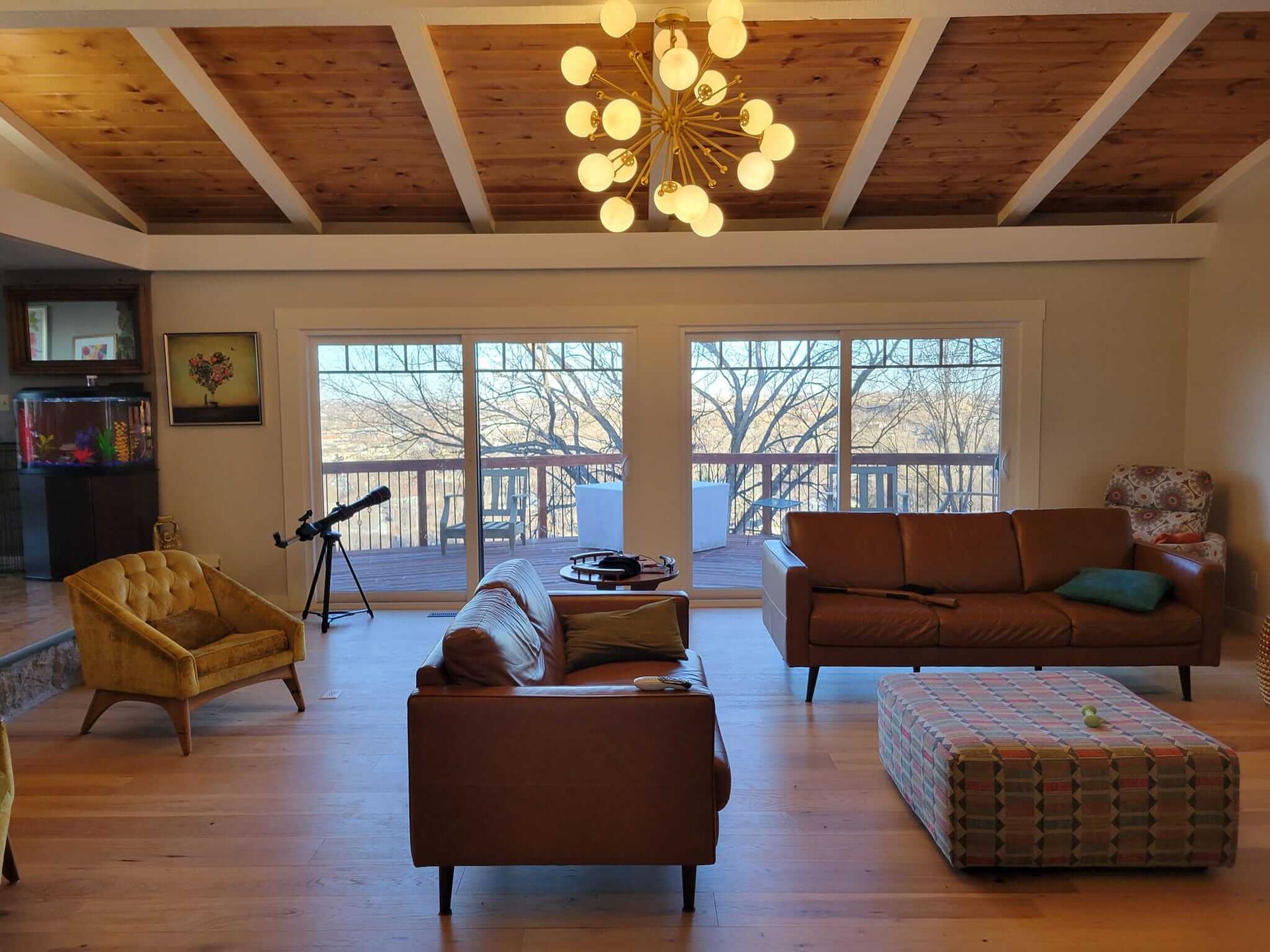 A living room with a couch, chairs, ottoman and a chandelier.