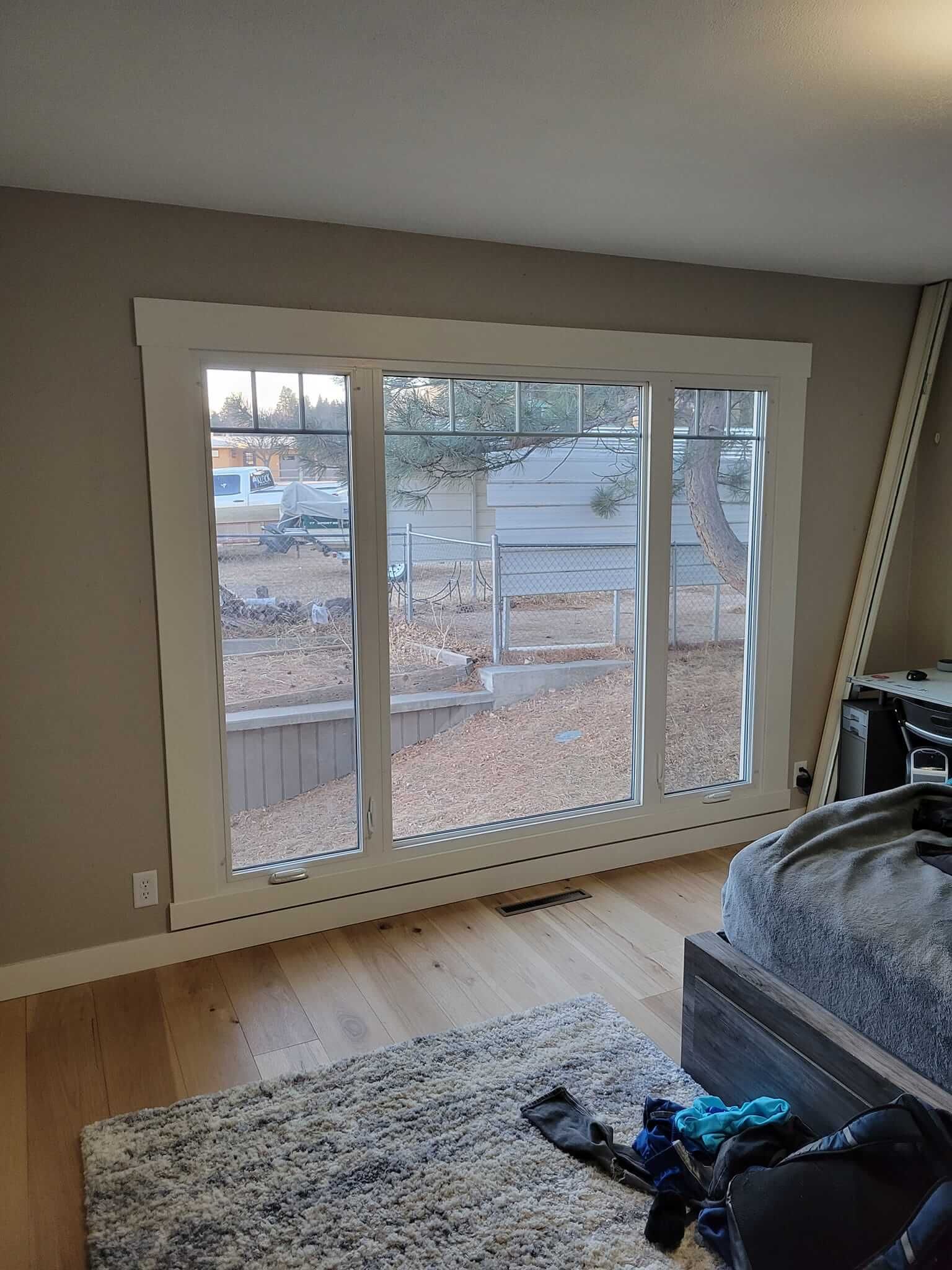 A bedroom with a large window and a bed.