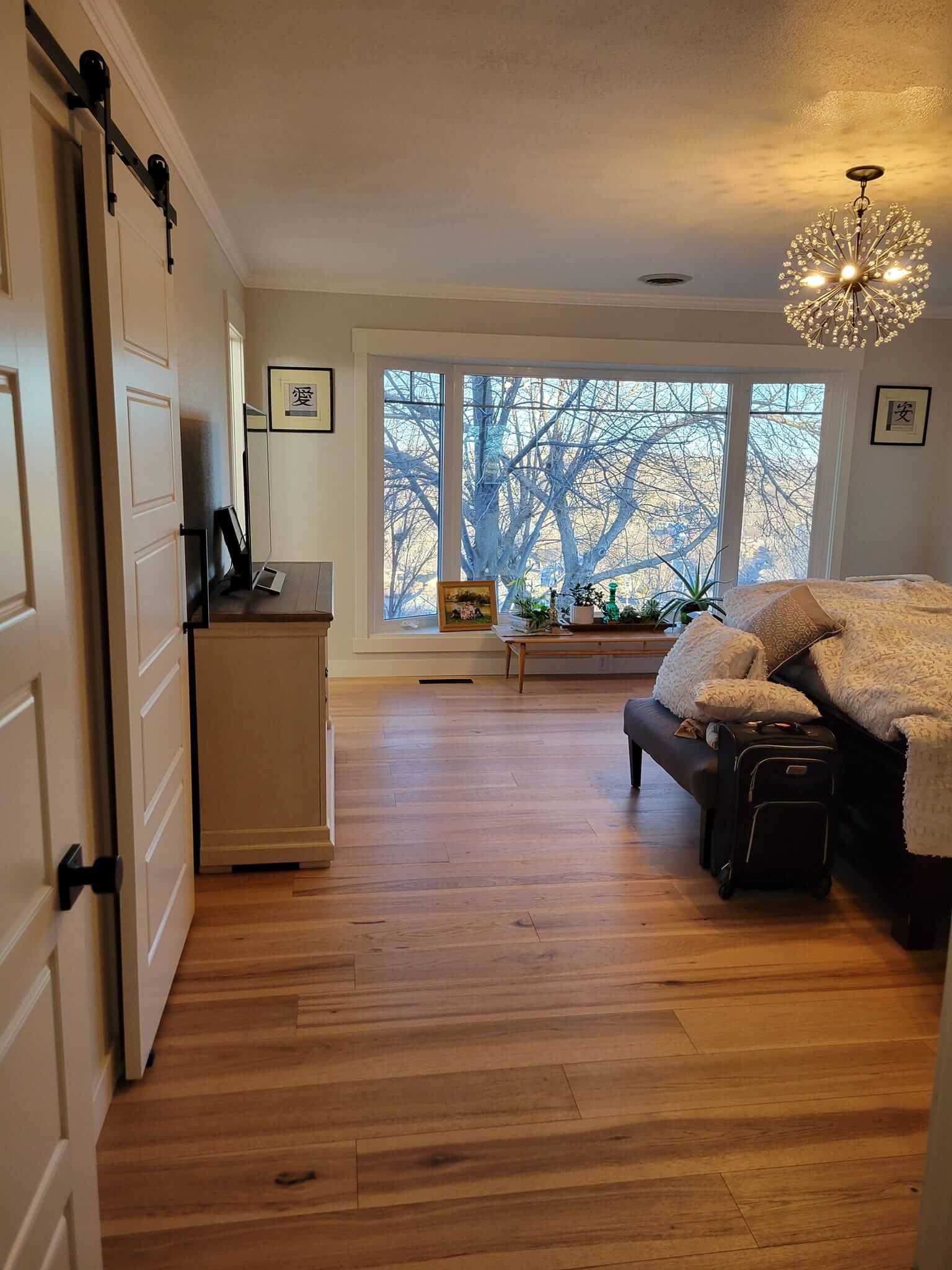 A bedroom with hardwood floors and a sliding barn door.