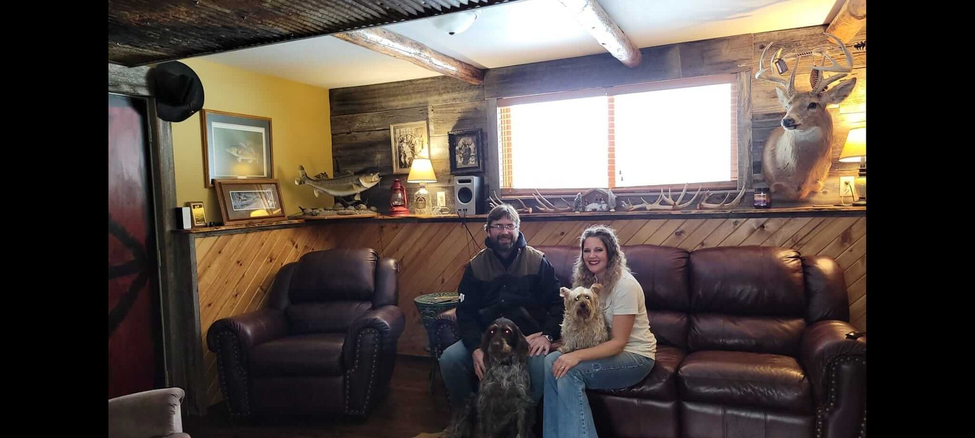 A man and woman are sitting on a couch with a dog in a living room.