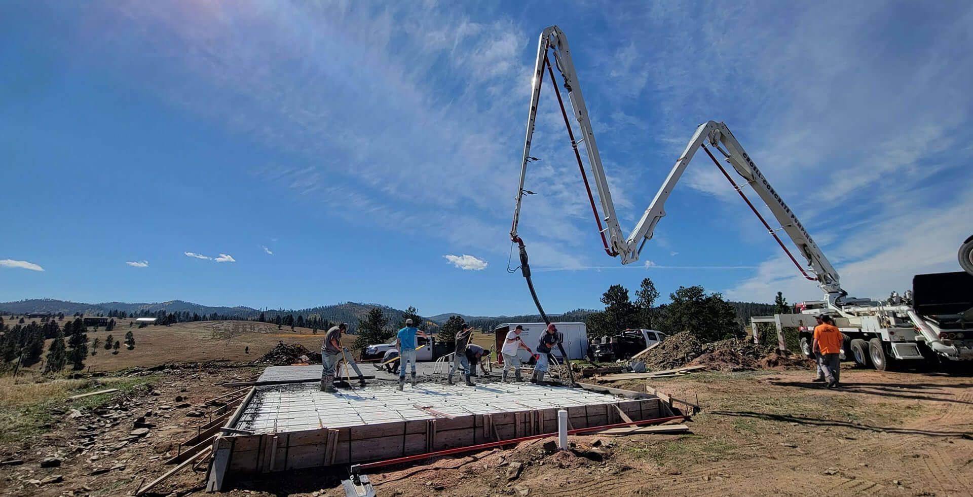 A concrete pump is being used to pour concrete into a foundation