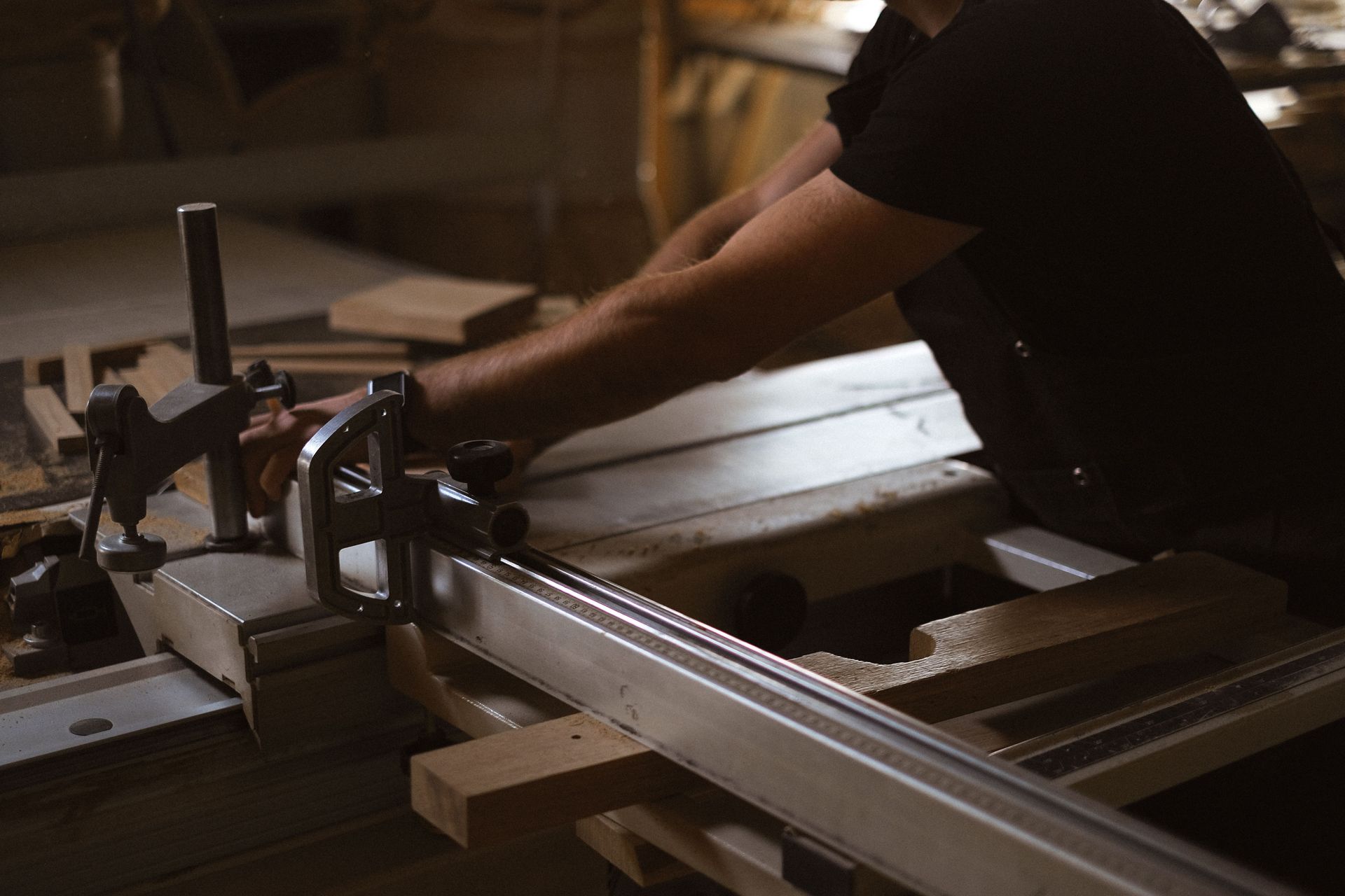 Person operating a woodworking saw in a dim workshop