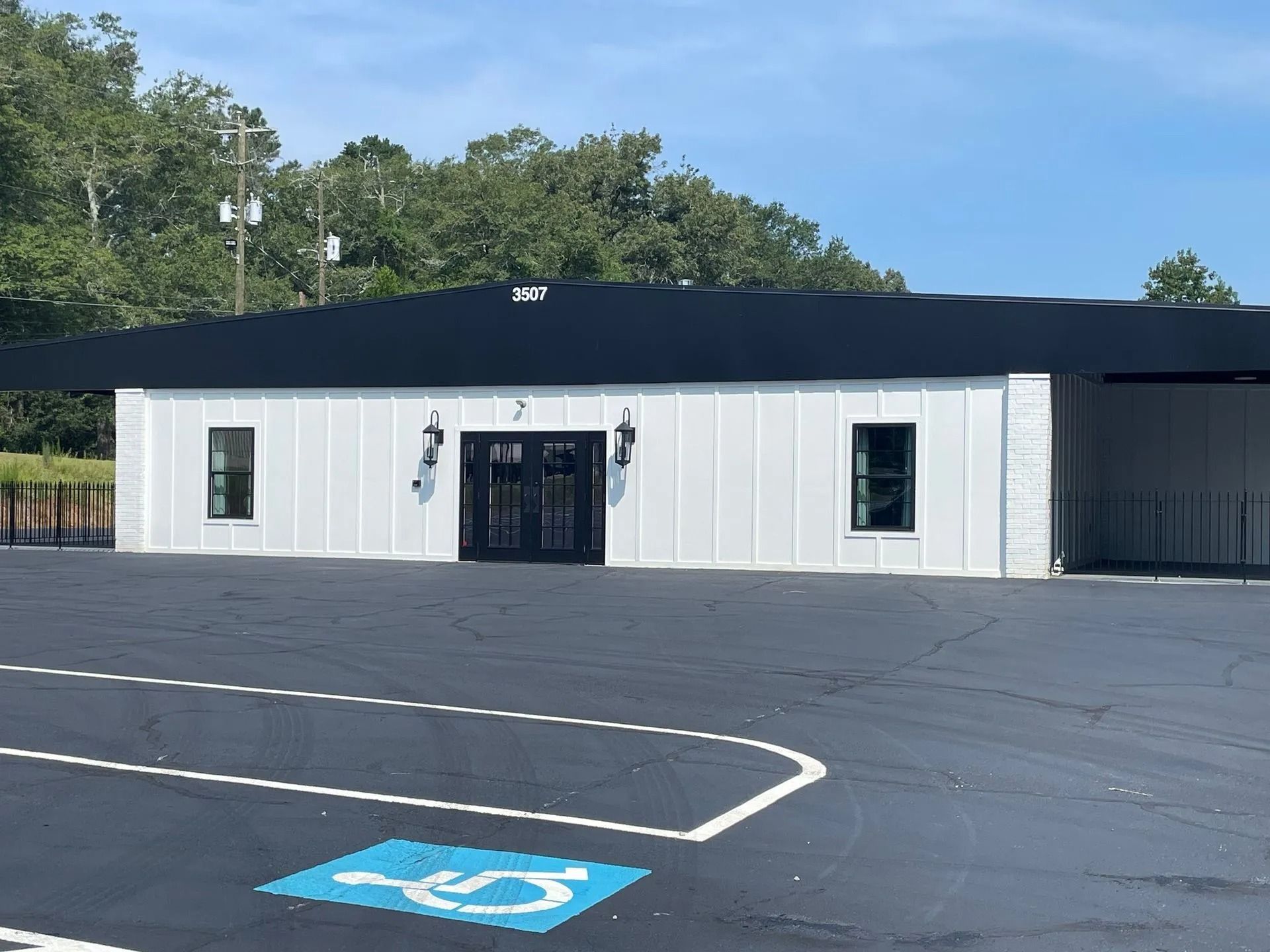 White building with black roof; handicap parking space visible in front.