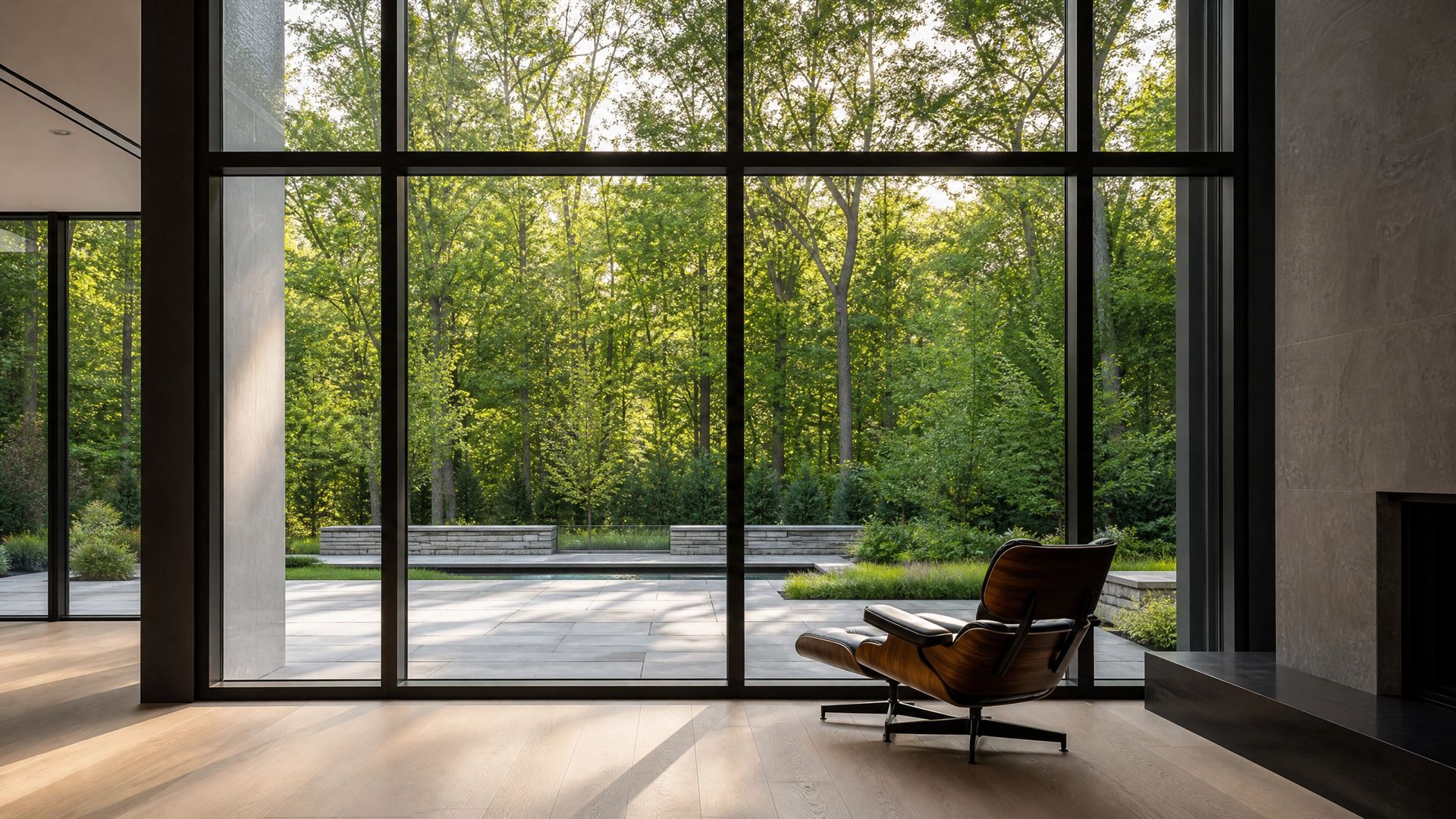 Modern living room with large glass doors, a lounge chair, and a view of a green outdoor terrace.