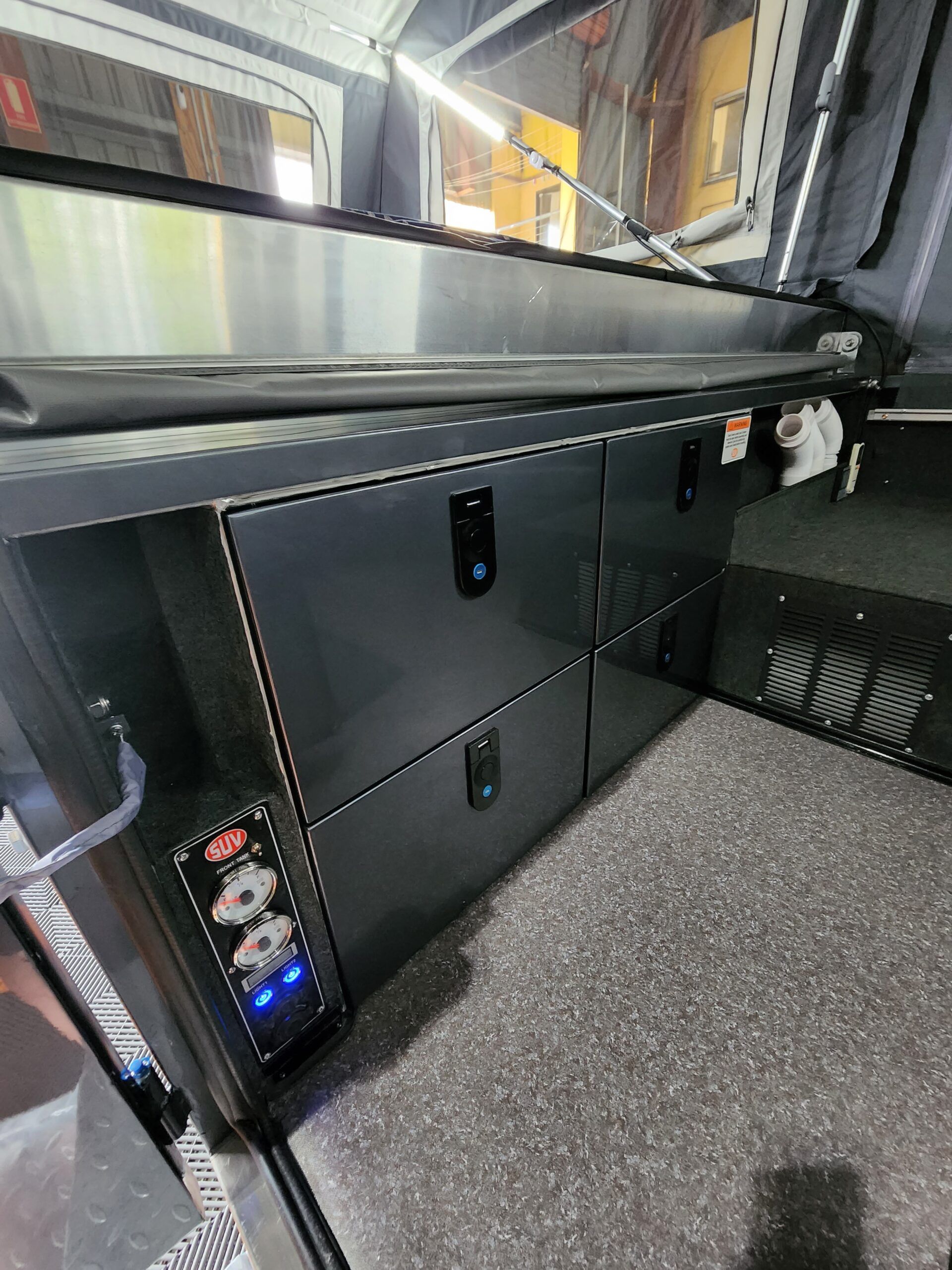 The inside of a truck with a bed and drawers.