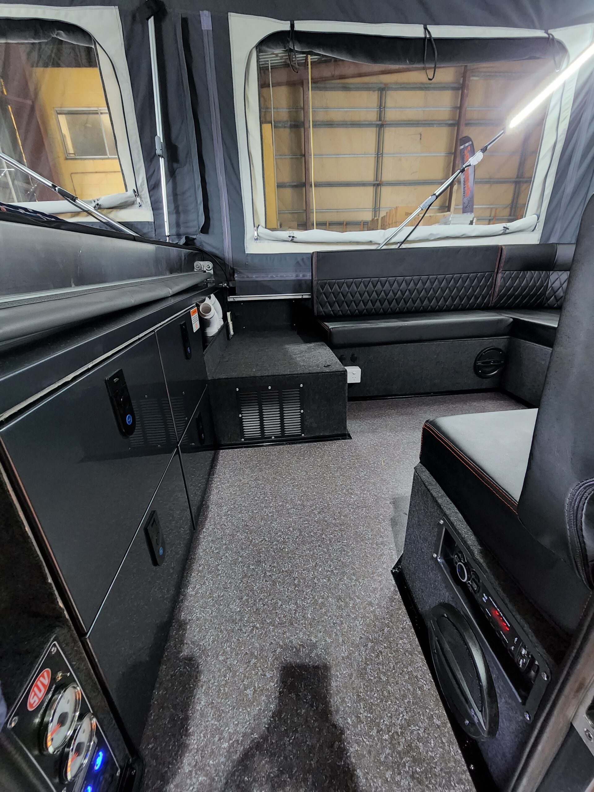 The inside of a camper with a couch and a refrigerator.
