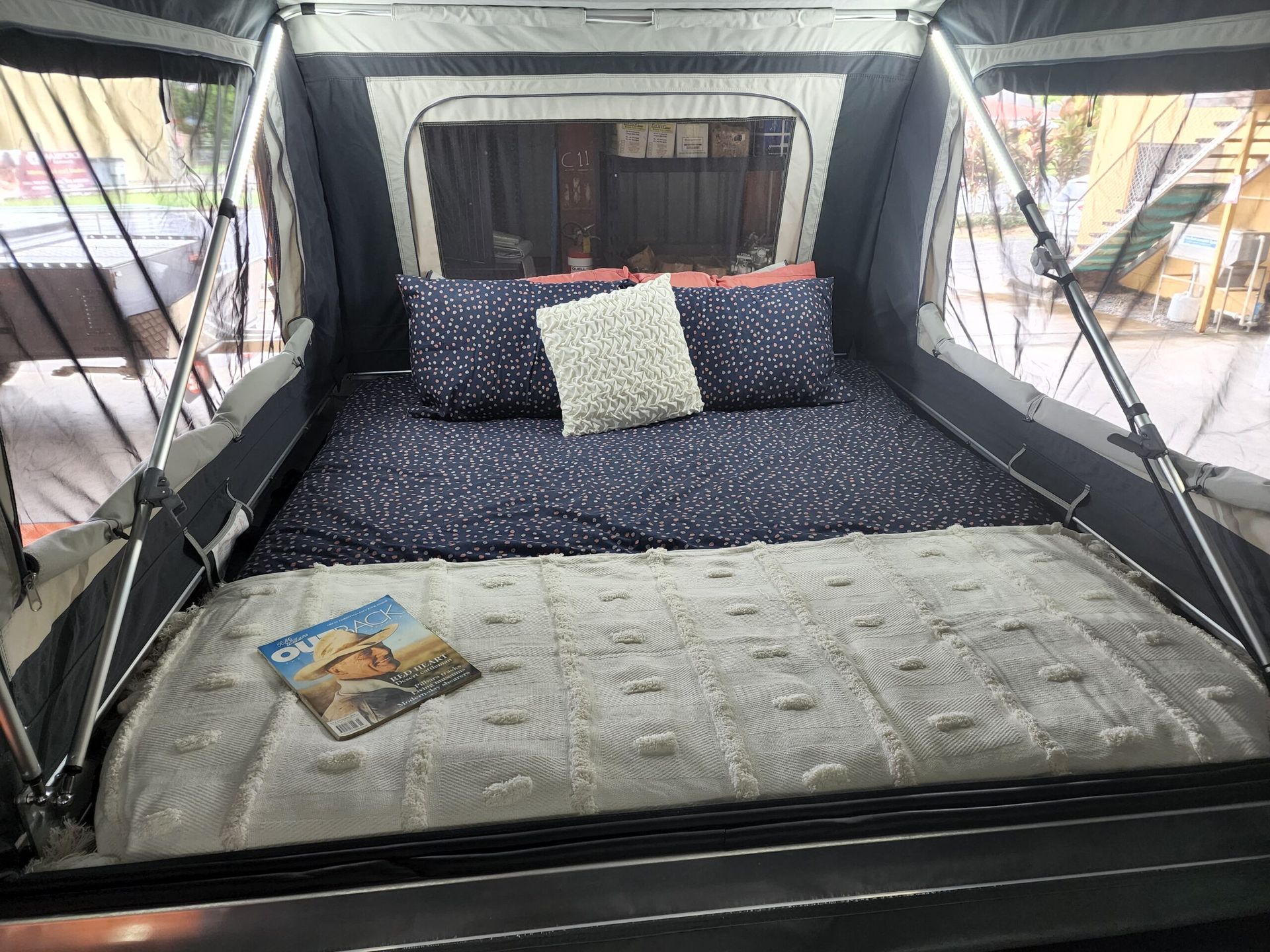 A bed in a tent with a magazine on it.