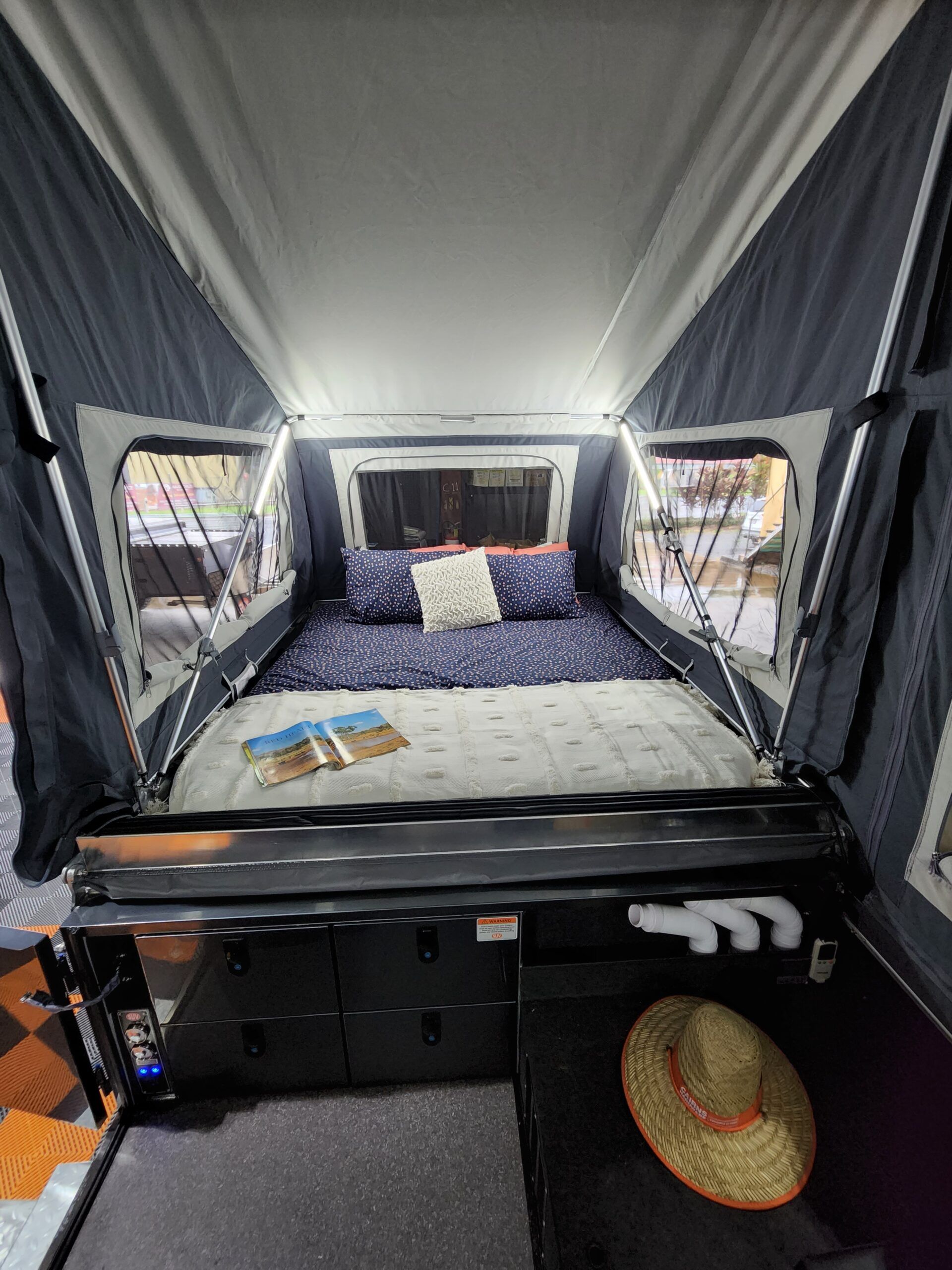 The inside of a camper with a bed and a straw hat.